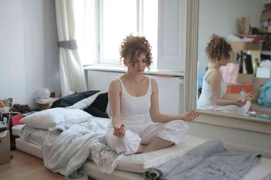 Девушка делает упражнения из йоги в кровати на полу